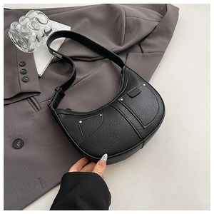 Detail of black lychee texture crescent bag with silver rivets and metal hardware