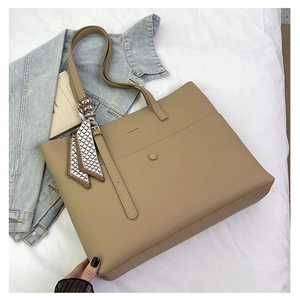 Detail of khaki tote bag with lychee texture, logo, silk scarf, and magnetic closure