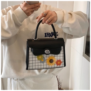 Close-up of black and white checkered handbag with handmade 3D crochet flower charms