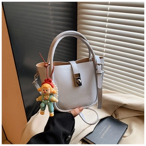 Detail view of light blue bucket bag with silver rotating lock and cartoon charm