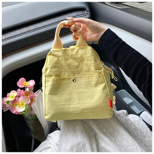 Light yellow waterproof nylon chest bag featuring a front pocket and hand-held strap detail