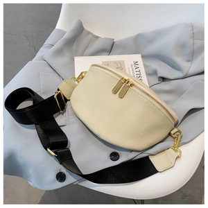 Detail of lychee textured cream crossbody bag with golden zippers on blue suit