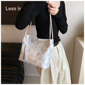 Detail showing butterfly embroidery and tassel on a traditional style bucket bag