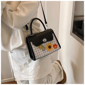 Détail du sac à bandoulière à carreaux noirs et blancs avec des appliqués de fleurs au crochet