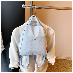 Detail of light blue versatile canvas backpack with front snap pocket and red side label
