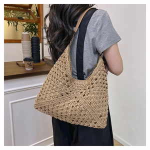 Detail of hand-woven straw shoulder bag with hollow mesh design and leather straps