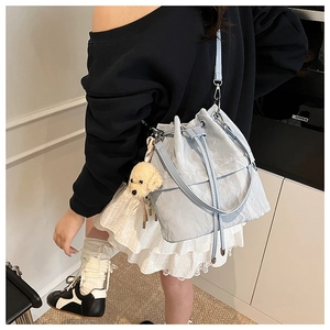 Detail of light blue pleated bucket bag with drawstring closure and cute puppy charm