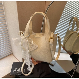 Detail of cream leather tote bag with pearl lace charm and textured finish