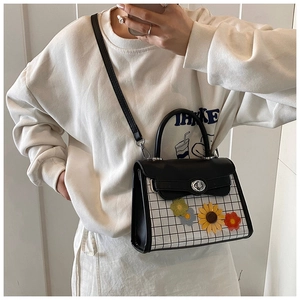 Détail d'un sac à carreaux avec fleurs 3D et fermeture à loquet en métal poli