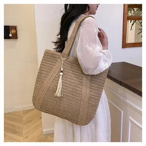 Detail of hand-woven straw tote bag featuring decorative wooden bead tassels and texture