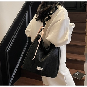 Detail of black tote bag featuring ruffled shoulder straps and pink drawstring accents