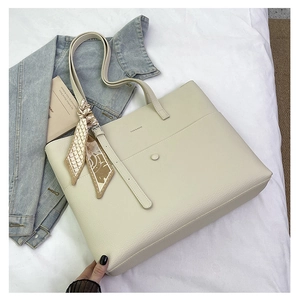 Detail of cream tote bag with pebble leather texture and decorative patterned scarf