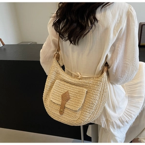 Detail of a beige woven straw hobo bag with brown leather strap and decorative pocket