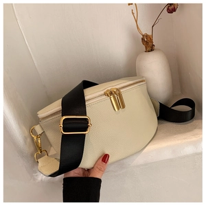 Detail of cream pebbled leather chest bag with gold hardware and black nylon strap