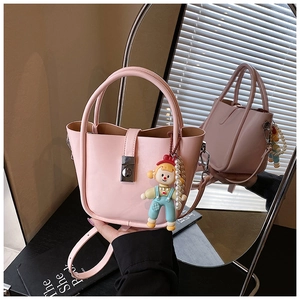 Detail of a pink bucket handbag featuring a silver buckle and a cute doll pearl charm