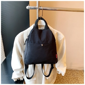 Detail of black nylon chest bag with magnetic buckle and red tag hanging on a white blazer