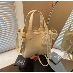 Detailed texture of white lychee leather bucket bag with pearl lace bow charm