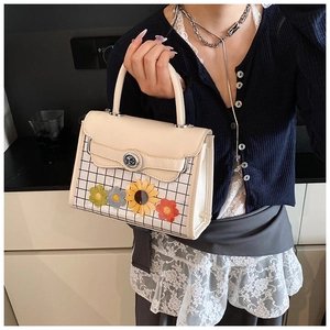 Détail de la broderie florale et du fermoir argenté sur le petit sac à main blanc