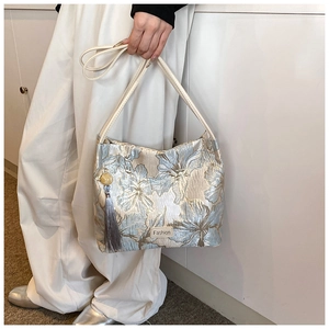 Detail view of floral jacquard fabric with grey tassel and cream shoulder strap