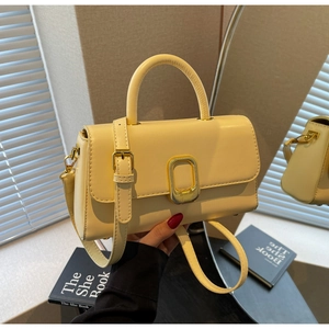 Détail du sac à main crème avec fermoir rotatif ovale doré et texture cuir synthétique