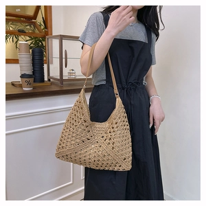 Close-up detail of beige crochet straw tote bag texture with brown leather strap