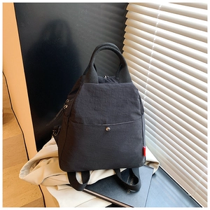 Detail of multi-functional black nylon chest bag with metal buckle flap and side red label