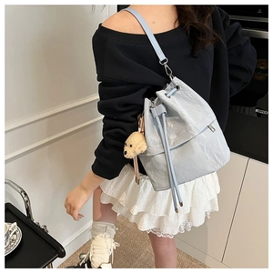 Detail of light blue pleated bucket bag with drawstring closure and cute dog plush charm