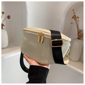Detailed macro of creamy white litchi texture on crossbody bag with gold metal zippers