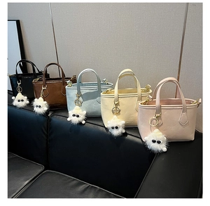 Close-up of five colorful PU leather tote bags with cute plush monster charms on a sofa