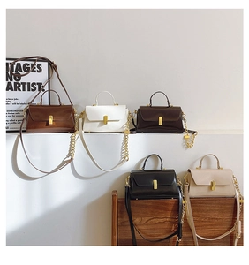 Close-up of elegant leather crossbody bags in five colors with gold metal turn-lock clasps