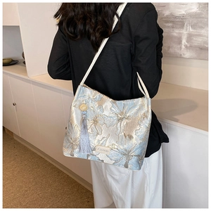 Detail of light blue jacquard shoulder bag with champagne floral pattern and tassel