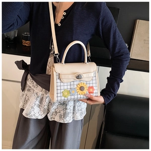 Détail du sac crème avec embellissements floraux 3D et motif à carreaux élégant