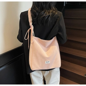 Detail of light pink tote bag featuring a decorative drawstring bow and branded woven label