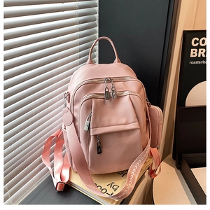 Pink pebbled leather backpack detail with multi-pocket design and decorative woven strap