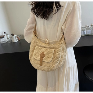 Detail of straw woven half-moon bag with leather buckle in a summer resort style