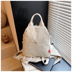 Close-up of beige nylon chest bag with a red fashion label and adjustable straps
