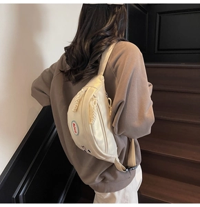 Dettaglio borsa a tracolla beige con cerniera in corda intrecciata e ricamo