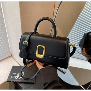 Détail du sac à main noir avec fermoir ovale doré et bandoulière réglable en cuir