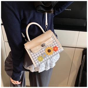 Détail du sac bandoulière à carreaux avec fleurs au crochet et fermoir rotatif en métal