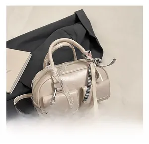 Detail showing beige PU leather bowling bag with front pockets and lace bow accents