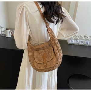 Detail of hand-woven straw bag with front leather pocket and adjustable strap