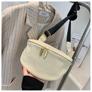Detail of off-white lychee grain leather crossbody bag with dual gold zippers and wide strap