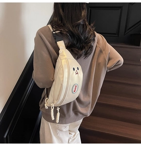 Dettaglio borsa a tracolla beige con ricamo a fumetto indossata da una modella
