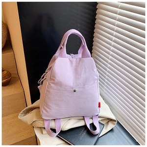 Detail of lavender multi-way bag showing buckle pocket and reinforced woven handles