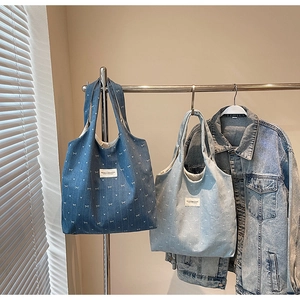 Detailed comparison of deep blue and light blue denim tote bags with white bow patterns