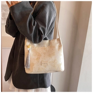 Detail of golden butterfly embroidery and grey tassel on beige Hanfu bucket bag