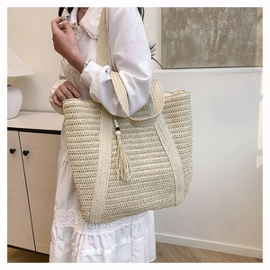 Detail of beige straw tote bag featuring honeycomb texture and wooden bead tassels