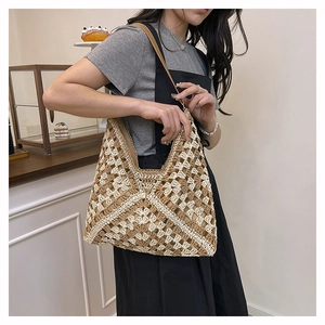 Detail of hand-woven straw tote bag with beige hollow pattern and brown leather strap