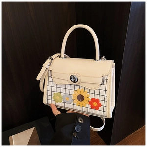Détail du sac à main blanc crème avec fleurs en tricot, motif à carreaux et fermoir argenté
