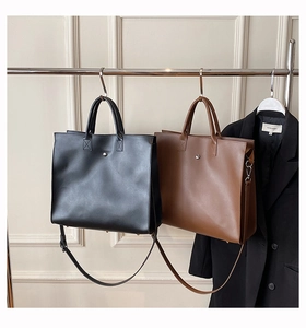 Detail view of large leather tote bags in black and brown with silver round buckles